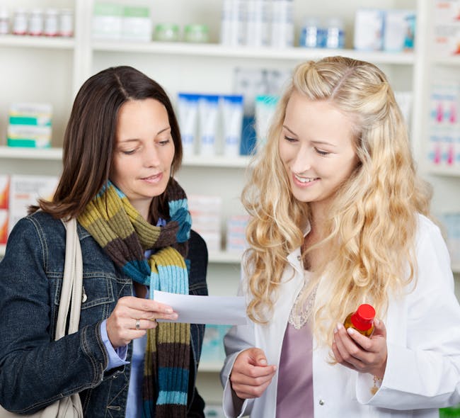 Two women smile as they look at over-the-counter products at Burrell Pharmacy.