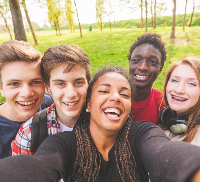A group of teens smile together.